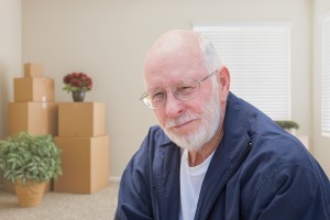 Senior Man in Empty Room with Packed Moving Boxes.